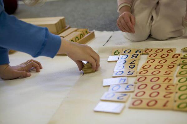 Child's hand using Montessori counting materials - Photo by Tacher School Milton - License CC BY SA 3.0